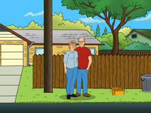 Load image into Gallery viewer, An elderly couple, both wearing specs, standing near the fence in this king of the hill style couples portrait.