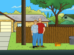 An elderly couple, both wearing specs, standing near the fence in this king of the hill style couples portrait.